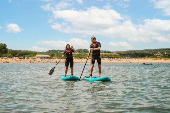 young couple stand up paddle boarding on oxwich bay