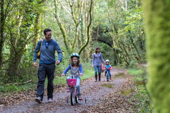 Parents helping two young girls on their bikes.
