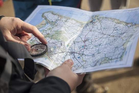 person holding a compass and a map