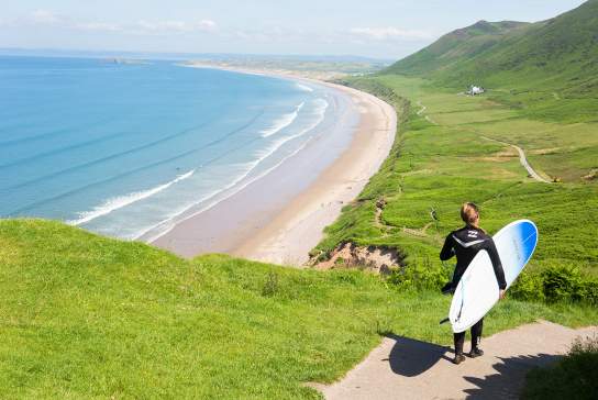 Surfer walking down to Rhossili Bay Beach