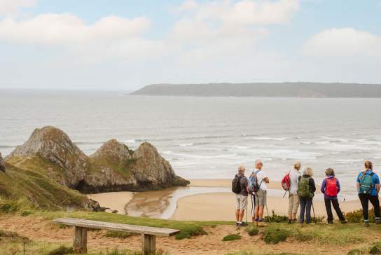A group of walkers looking out at Three Cliffs Bay.
