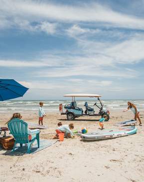 A family set up on the beach with games and a golf cart.