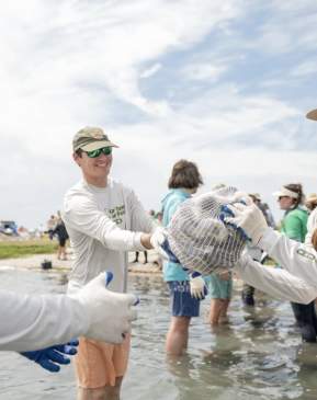 A group of people passing bags of oyster shells down a line.