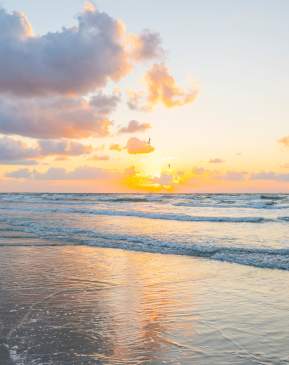 A bright, golden sunrise over the ocean waves on a beach in Port Aransas.