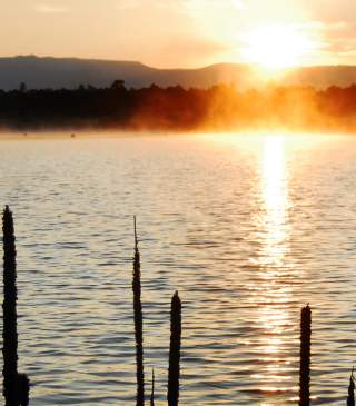 The sun hangs low at sunset over Heron Lake State Park in New Mexico.