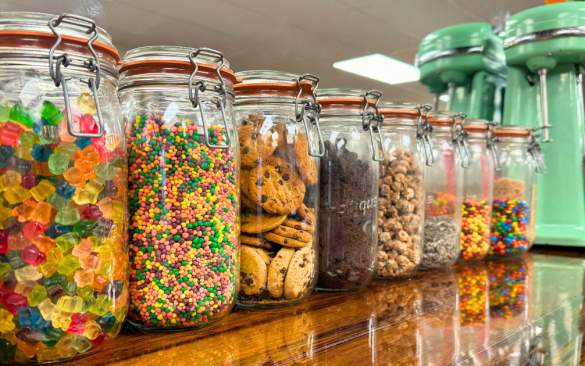 jars of candy and cookies lined up on the ice cream parlor bar.