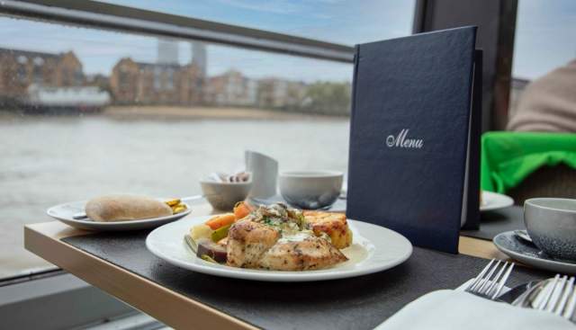 Food on a plate in front of window on the river.