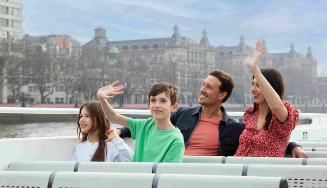 Family on the top deck of City Cruises boat on the Thames in London