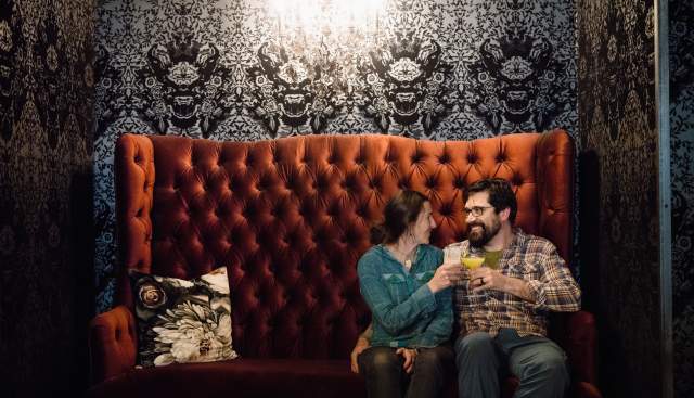 Couple sitting on oversized couch toasting at Lake Effect