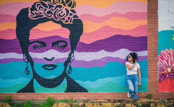 Woman leaning on the wall next to the Frida Kahlo mural in downtown Beaumont