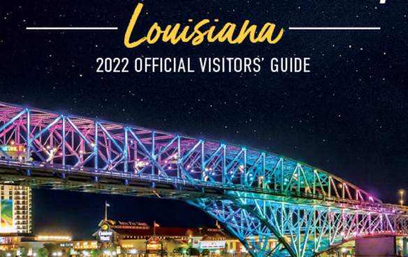 2022 Visitors' Guide Cover Cropped - LED-lit Bakowski Bridge of Lights on the Texas Street Bridge over the Red River in foreground, background of Bossier City skyline at night