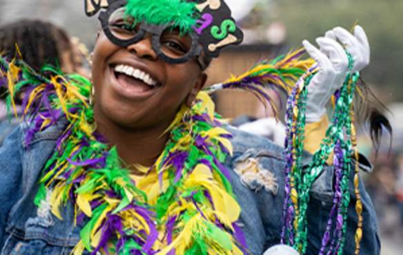 Woman celebrating Mardi Gras with mask, boa and Mardi Gras beads
