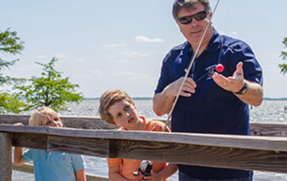 Man and grandsons fishing from lake pier at Caddo Lake