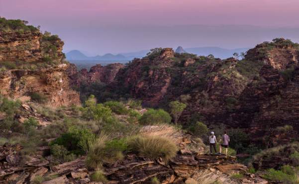 A couple standing on the rock formations in Mirima National Park at, with deepending pink colours in the sky