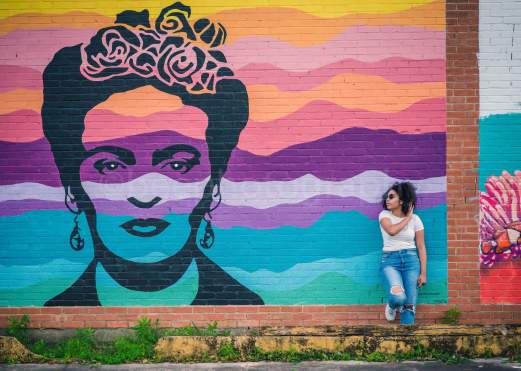 Woman leaning on the wall next to the Frida Kahlo mural in downtown Beaumont