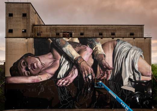 Artist Drew Merritt painting the Genesis Mural for the Beaumont TX Mural Festival
