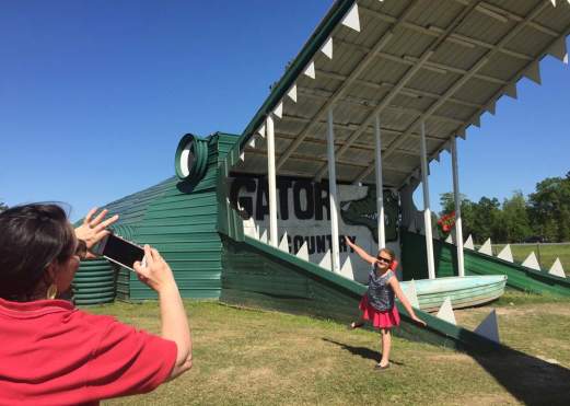 Parent taking a picture of a little girl posing in front of Big Beau at Gator Country Adventure