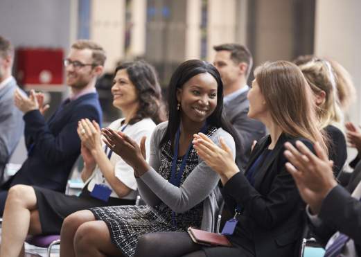Attendees sitting in a meeting clapping