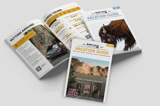 Black Hills & Badlands Vacation Guide with the summer cover, the winter cover, and opened to a page