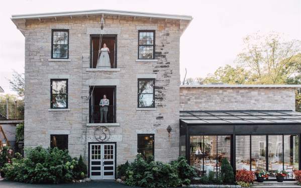 Bride and groom stand on 2nd and 3rd balcony of the Sinclair of Skaneateles, an industrial wedding venue.