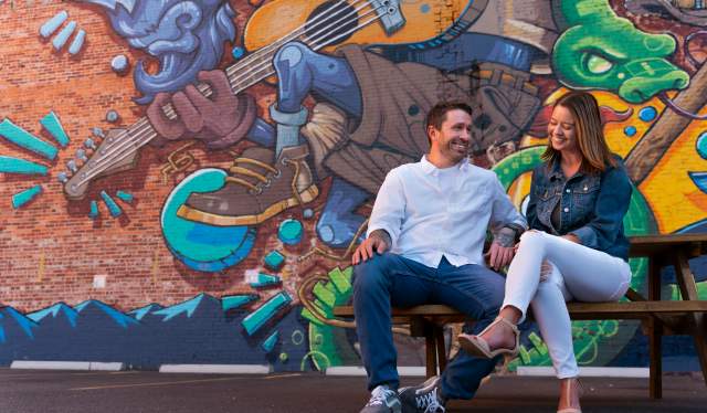 Airbnb Cheyenne WY-A couple sits on a bench talking with a giant mural behind them
