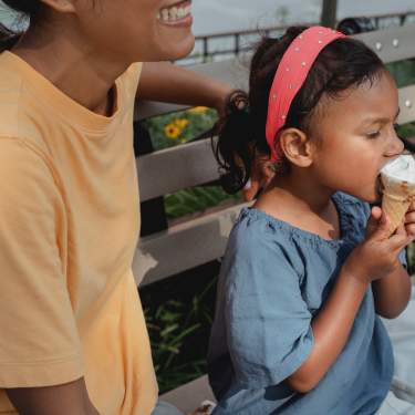 Little Girl Eats Ice Cream Next to her Mom