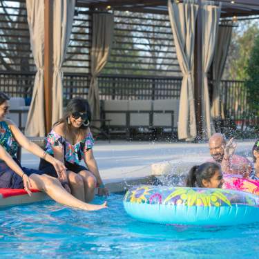 Mom, dad, two girls, and grandmother splash and play in hotel pool