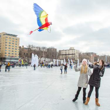 Two white women fly a kite while standing on a frozen Lake Mendota