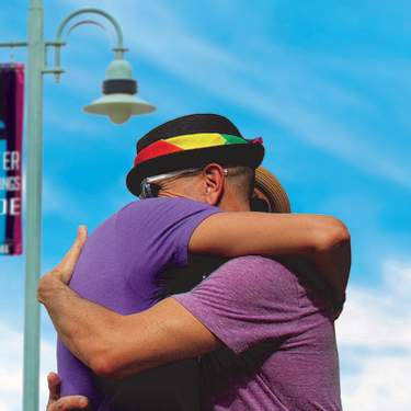 Couple hugging under GPS Pride flag
