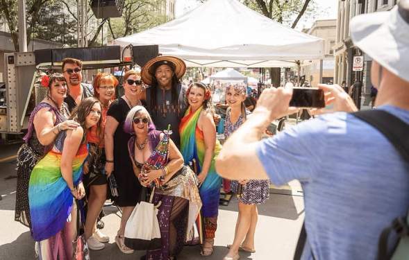 A group of people wearing colorful clothing getting a group photo taken at Ann Arbor Pride