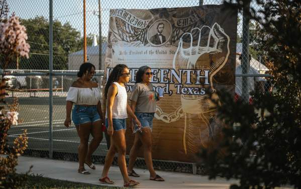 Women walking in front of the Juneteenth Banner posted at Cecil Holman Park for the Fun in the Park event