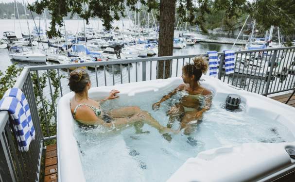 Two women soak in a hot tub overlooking the marina.