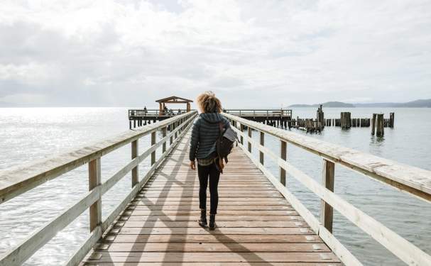 A woman wearing a backpack walks along the pier.