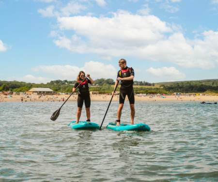 young couple stand up paddle boarding on oxwich bay