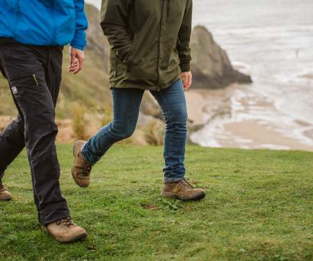 Legs of two walkers near the coast.