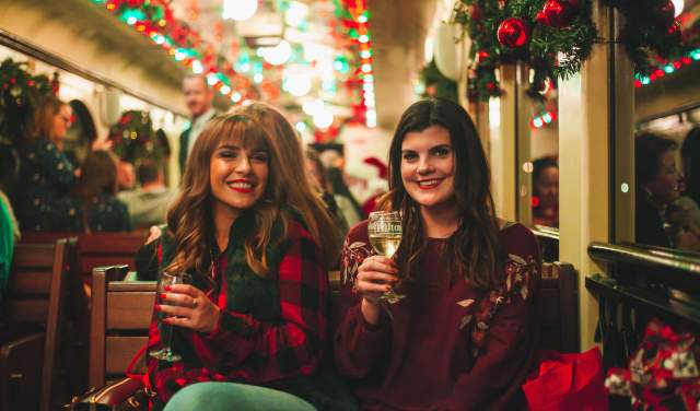 Two women with glasses of wine aboard the Christmas Wine Train