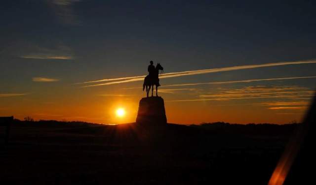 A statue of a man on a horse at sunset