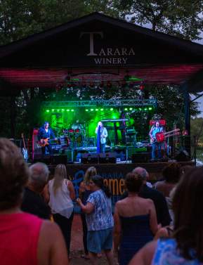 Crowd dancing at an evening outdoor concert on a covered winery stage in Loudoun Virginia.