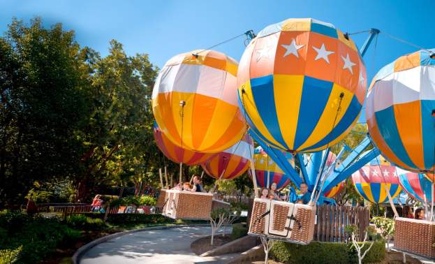 Lush trees next to the Balloon Flight ride with colorful hot air balloons and baskets that spin in around in this thrilling ride.