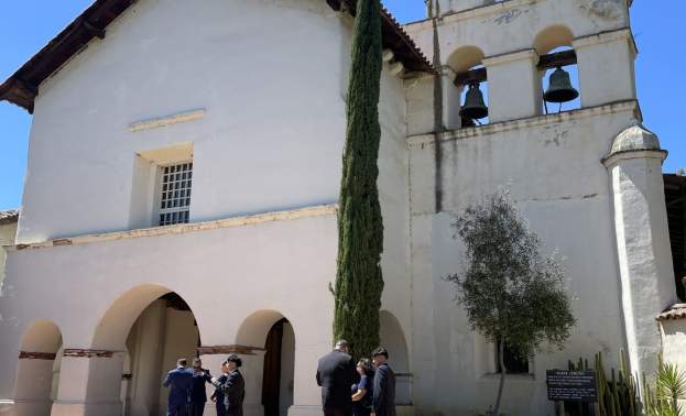 San Juan Bautista Mission. People stand in front of the Mission entryway and Bell Tower.