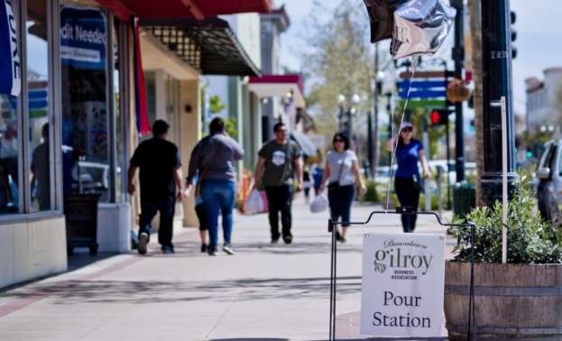 people walk along the sidewalk downtown by businesses