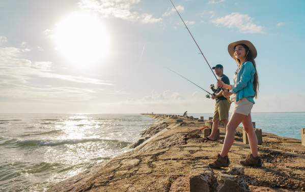 Father and daughter fishing off the jetties on a sunny bright day