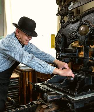 A man using a vintage printing press in the Museum of Lincolnshire Life