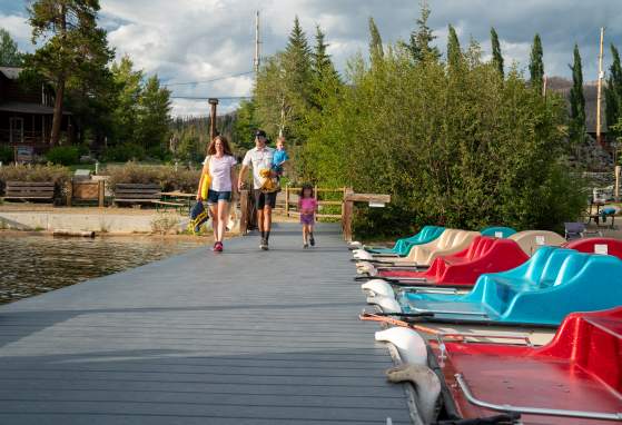 Family walks on dock next to glittering pedal boats