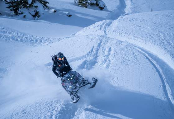 Snowmobile going over a hill in deep snow