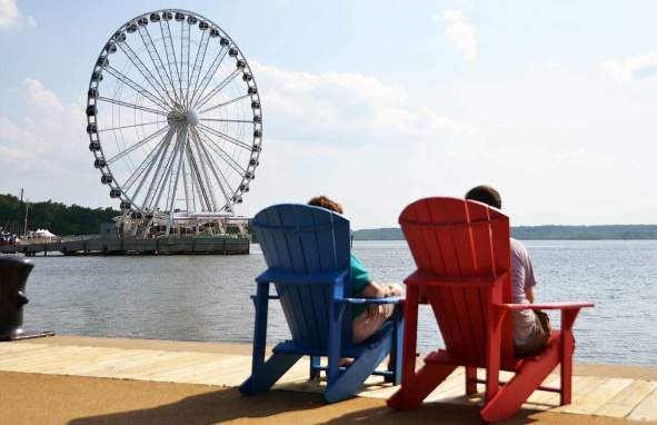People sitting in chairs with a beachfront view of the Oxon Hill Capital Wheel In Prince George's County, MD