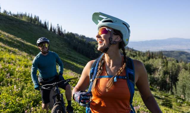 a guy and girl mountain biking in the summer