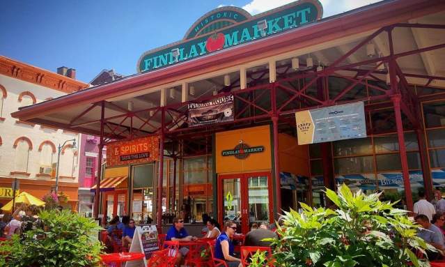 The entrance of Findlay Market during the day with couples sitting at tables surrounded by flowers.