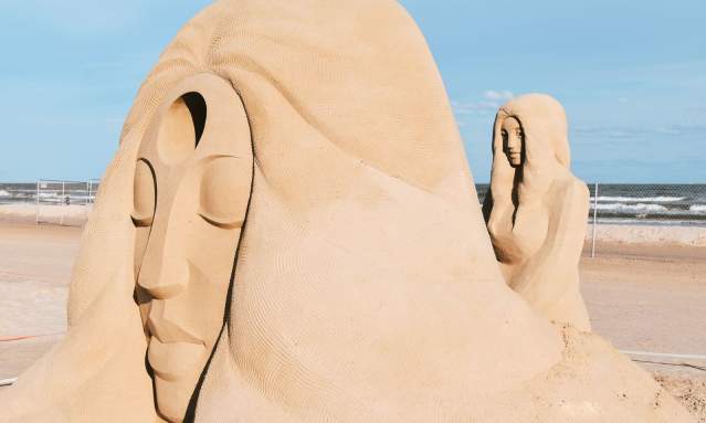 A large sand sculpture of a person's face resting on a hand at Texas SandFest.
