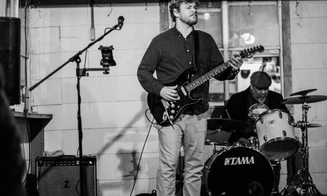 Black and white image of a man singing and strumming a guitar.